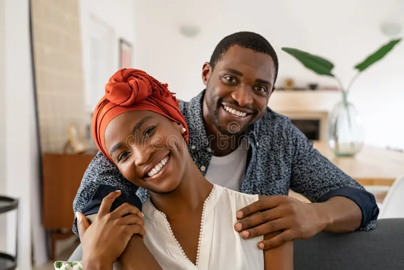 cheerful-black-couple-embracing-home-portrait-mid-adult-happy-african-american-couple-hugging-home-sitting-couch-234879204